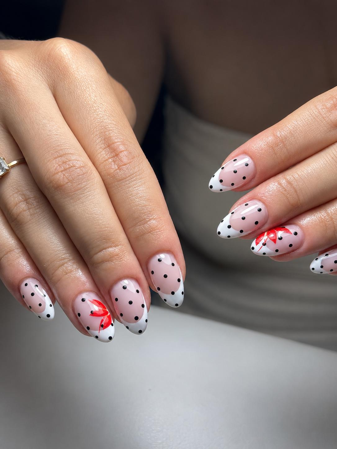 Diseño de uñas con lunares y lazo rojo